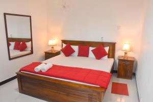 a bedroom with a bed with red pillows and a mirror at Cozy Homestay Kandy in Kandy