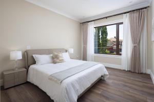 biała sypialnia z łóżkiem i dużym oknem w obiekcie Vancouver Vacation Home w mieście Richmond