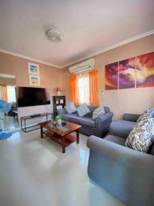 ein Wohnzimmer mit 2 Sofas und einem TV in der Unterkunft Mi Casa Gensan - Beautiful 2BR house with wifi & netflix in General Santos