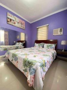 - une chambre avec un grand lit aux murs violets dans l'établissement Mi Casa Gensan - Beautiful 2BR house with wifi & netflix, à General Santos