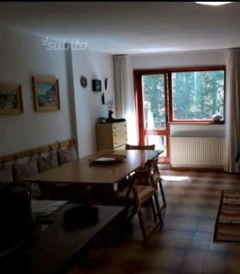 uma sala de estar com uma mesa de madeira e uma grande janela em La casa di Silvano em Cerreto Laghi