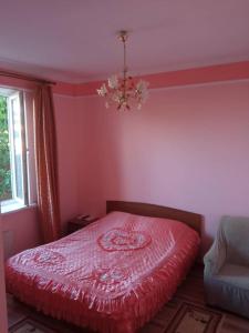 a bedroom with a red bed and a chandelier at Гостевой дом "Ысык-Куль - Светлана" in Cholpon-Ata