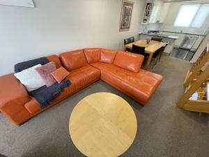 a living room with a leather couch and a table at Angala 1 Lovely Woodridge 2-Bedroom Apartment in Thredbo