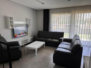 a living room with a couch and a tv at Villa Ögreten in Aydın