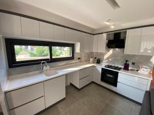 a kitchen with white cabinets and a window at Villa Ögreten in Aydın
