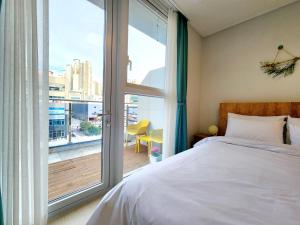 a bedroom with a bed and a large window at Well stay in Incheon