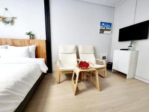 um quarto com duas cadeiras e uma cama e uma televisão em Well stay em Incheon
