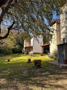 una casa en un patio con un árbol en Cabañas El Francés en Merlo