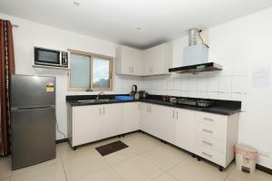 a kitchen with white cabinets and a stainless steel refrigerator at Tropical Plaza Apt in Nadi