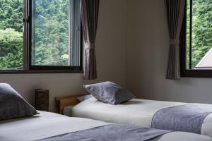 two beds in a room with two windows at YOICHI inn HAKONE in Hakone