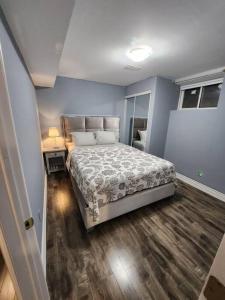 a bedroom with a large bed and a wooden floor at Adorable 2-Bedoom walkout basement Apartment in Milton