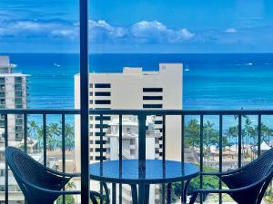 a table and chairs on a balcony with a view of the ocean at Jenny's Pineapple Cottage in Honolulu