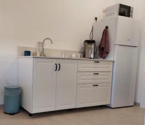 eine weiße Küche mit einer Spüle und einem Kühlschrank in der Unterkunft נצר- צימר 
