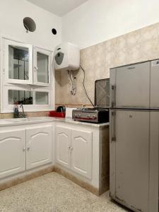 a kitchen with white cabinets and a refrigerator at Dar almasyaf, maison bord de mer in Gabès