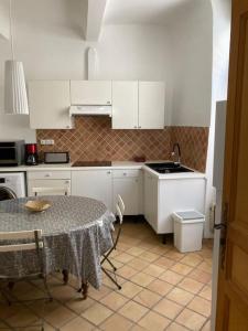 a kitchen with a table and a sink and white cabinets at La Célestine in Valensole +14 photos
