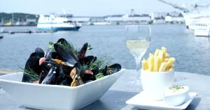 a bowl of food and a glass of wine and a plate of french fries at Husbåten Vega 2 Göteborg City in Gothenburg
