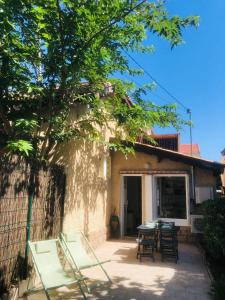 um pátio com cadeiras e mesas em frente a uma casa em Maisonnette climatisée refaite à neuf avec parking à 300m de la plage em Le Grau-dʼAgde