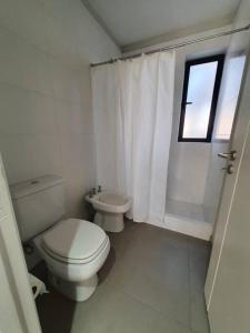 a white bathroom with a toilet and a window at Bosques de Mayo - Departamento 1 in Maipú