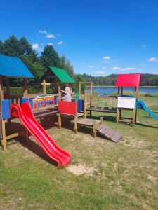 um parque infantil com escorrega em Leśny dworek - pokoje nad jeziorem em Koczała