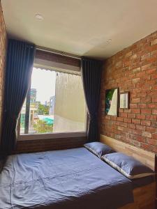 a bed in a room with a brick wall at IKIGAI Dorm Hostel - Danang Beach in Da Nang