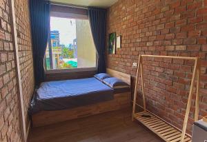 a small room with a bed and a brick wall at IKIGAI Dorm Hostel - Danang Beach in Da Nang