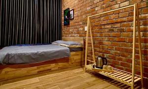 a bedroom with a bed and a brick wall at IKIGAI Dorm Hostel - Danang Beach in Da Nang