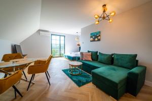 Apartamenty Mazurskie في ميكووايكي: غرفة معيشة مع أريكة خضراء وطاولة