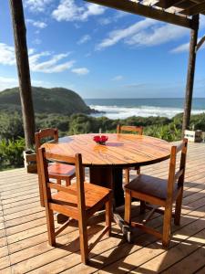a wooden table and chairs on a deck at CORAM DEO SaltyWaves double en-suite rooms with sea views in Coffee Bay