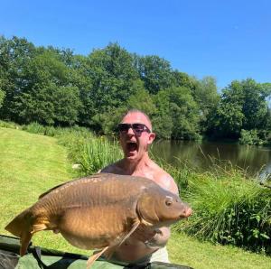 un uomo che tiene un pesce di fronte a un corpo d'acqua di Lac Cimes a Pagéas Altre 19 foto