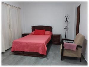 a bedroom with a red bed and a chair at Casa Oliveros in Sunampe