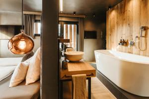 un bagno con vasca, lavandino e letto di ALMMONTE PRÄCLARUM SUITES Design Hotel a Wagrain