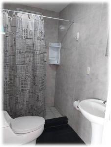 y baño con cortina de ducha, aseo y lavamanos. en Casa Oliveros en Sunampe