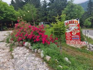 un giardino fiorito con fiori rosa accanto a un cartello di Guesthouse Alberti Llogara a Shalë