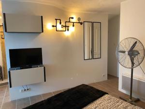 ein Wohnzimmer mit einem TV und einem Ventilator in der Unterkunft La vue sur le Mont Ventoux, appartement & parking in Cairanne