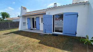 a white house with blue doors and a yard at Maison avec jardin, quartier calme, 2 chambres - plain pied in Saint-Hilaire-de-Riez