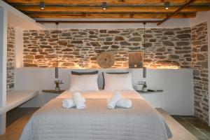 a bedroom with a large bed with a stone wall at Celini villa Tinos in Krokos
