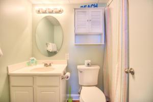 a bathroom with a toilet and a sink and a mirror at 1112 Relax Life Is Good by Atlantic Towers in Carolina Beach