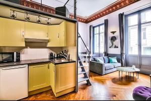a kitchen with yellow cabinets and a living room at Appartement Chic & Baroque avec parking sécurisé in Avignon