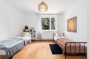 2 bedden in een witte kamer met een raam bij Spacious Family Apartment Promienista 1,5 km to Hala Arena Poznań by Renters in Poznań