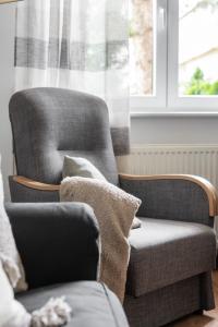 una silla y un sofá en una habitación con ventana en Spacious Family Apartment Promienista 1,5 km to Hala Arena Poznań by Renters en Poznan