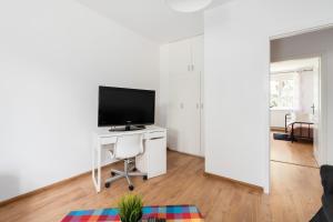 een woonkamer met een televisie en een bureau met een stoel bij Spacious Family Apartment Promienista 1,5 km to Hala Arena Poznań by Renters in Poznań