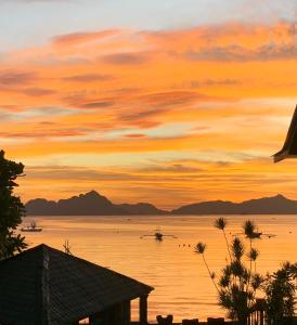a sunset over the water with mountains in the background at Morning Walsh Resort in El Nido