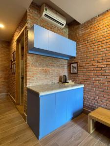 a kitchen with blue cabinets and a brick wall at IKIGAI Dorm Hostel - Danang Beach in Da Nang