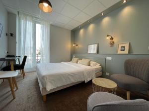 a bedroom with a bed and a table and chairs at Cit'Hotel Les Alizes in Dinard