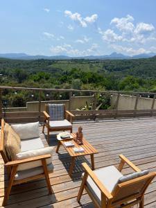 a deck with chairs and tables and a view of the mountains at Villa Héliopolis in Ventiseri