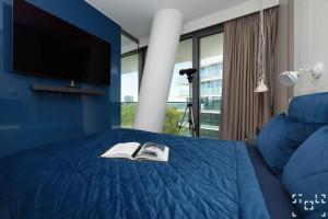 a bedroom with a blue bed with a tv and two books at Wave Międzyzdroje - Luxury 2 Bedroom Suite with Salon and Kitchen in Międzyzdroje