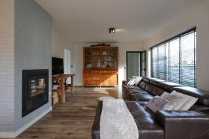 a living room with a leather couch and a fireplace at Villa De Strandjutter in Nieuwpoort