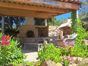 un patio con mesa de picnic y horno de piedra en Mas des rochers - Romance tropicale, en Le Beausset