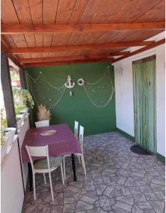 un patio con mesa, sillas y una pared verde en Sandra Apartmani 3 en Zaostrog