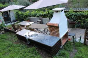 a barbecue grill with a table and an umbrella at Cantinho Casal do Rei in Seia